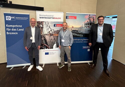 Matthias Böhm, Arne Klarmann und Thorben Wilking stehen vor drei Roll-up-Bannern des Bremerhavener Wirtschaftsdialoges.